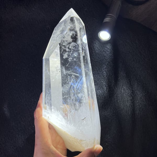 Torch beam on a black background picking out blue needle inclusions