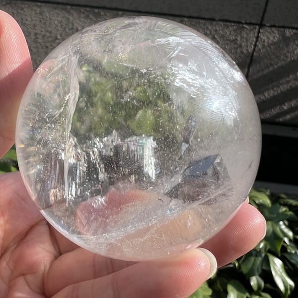 Sphere held against a building wall showing clarity and dark inclusions