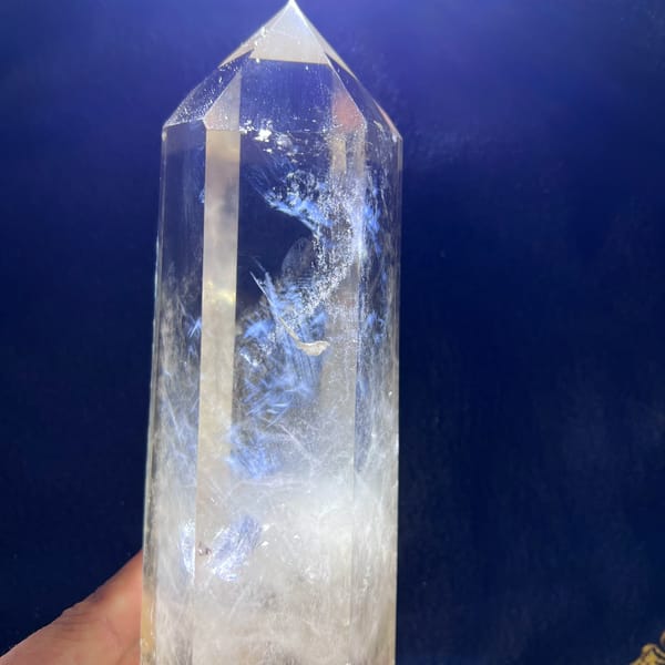 Polished quartz tower on a blue backdrop with a curling blue needle plume