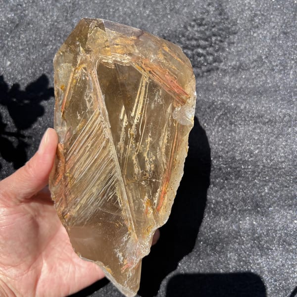 Smoky quartz held in the hand showing the fishbone inclusions clearly