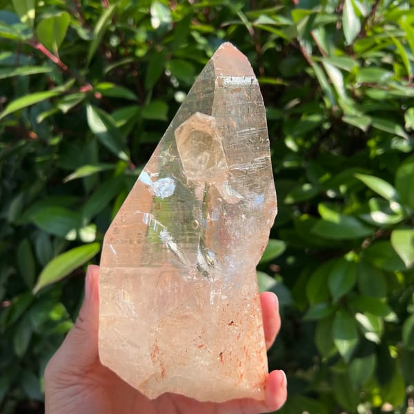 Clear quartz crystal turned to show the small attached scepter and white spot