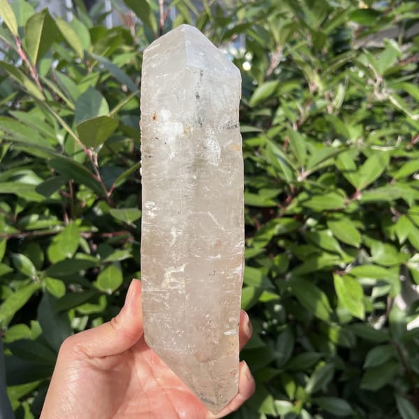 Clear quartz crystal held upright showing its full double-pointed length