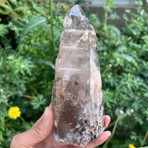 Freeform quartz point with clear tip and smoky patches near the base
