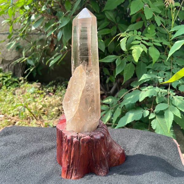 Smoky quartz point on its stand, viewed from the side with smaller attached crystal