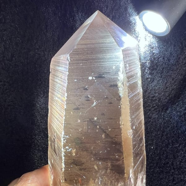 Torchlit close-up of the polished tip revealing faint white phantom pyramids