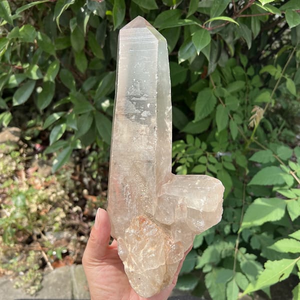 Smoky quartz point upright in hand with secondary crystal near the base