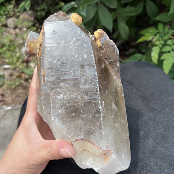 Old-stock quartz held in hand showing striated faces and rusty base