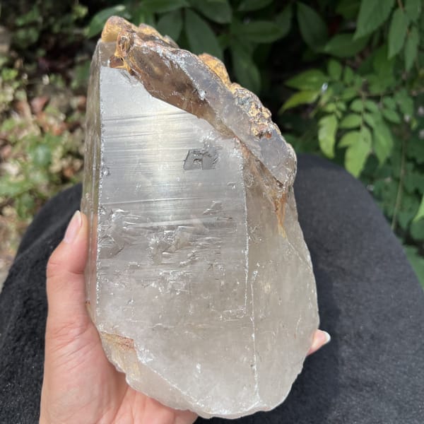 Quartz in hand with horizontal striations and crust along the edge