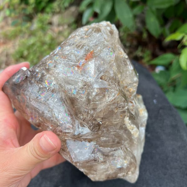 Smoky quartz skeletal crystal with fluid trails and rust-red spot