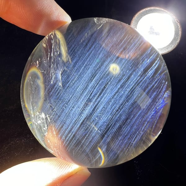 Sphere under torchlight with blue needles and a small rainbow arc