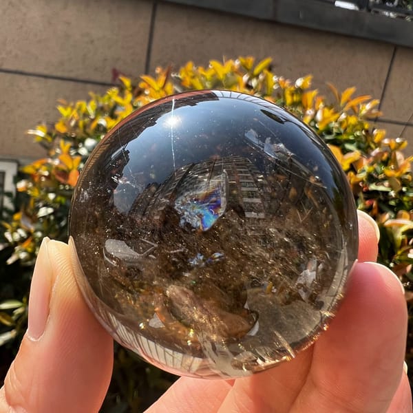 Smoky quartz sphere with a rainbow flash and inner clouds