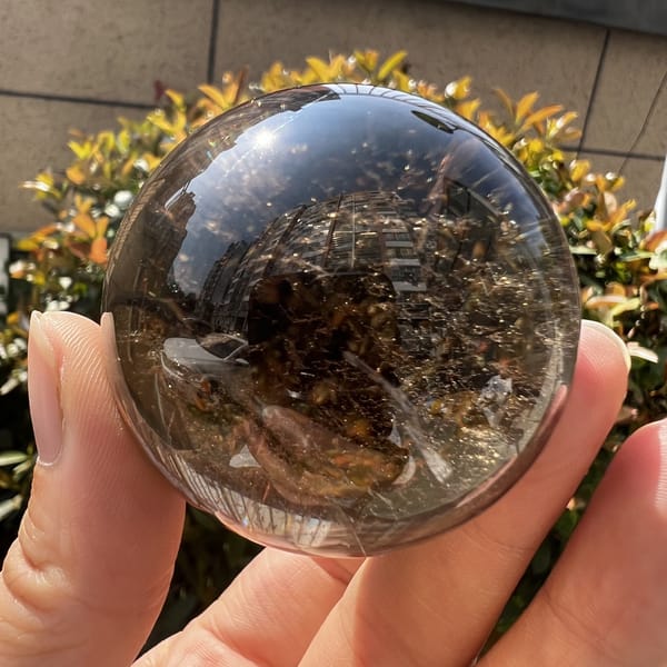 Smoky quartz sphere in daylight showing deep brown interior