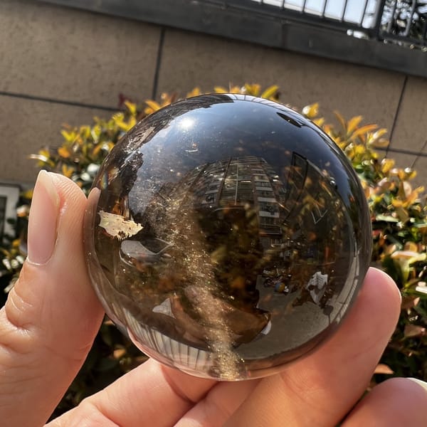 Smoky sphere with the white flake inclusion and golden needle band