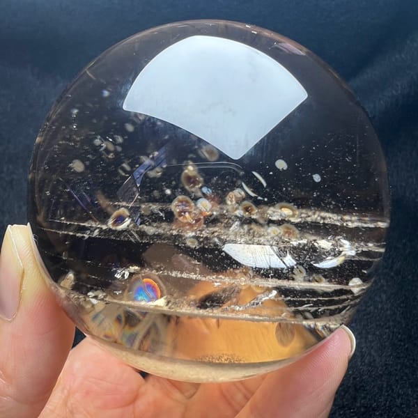 Himalayan smoky quartz sphere with parallel phantom lines and small rainbows