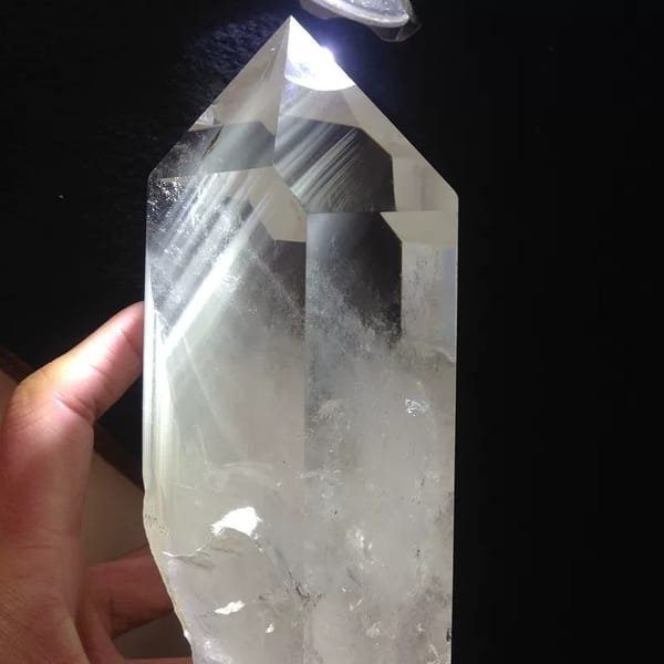 Backlit clear point on black, white phantom streaks inside the crystal