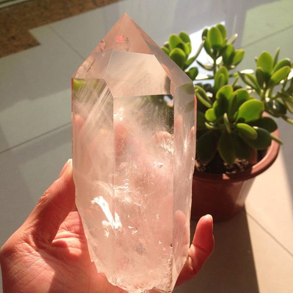 Quartz point in daylight with sunlit white streaks below the tip