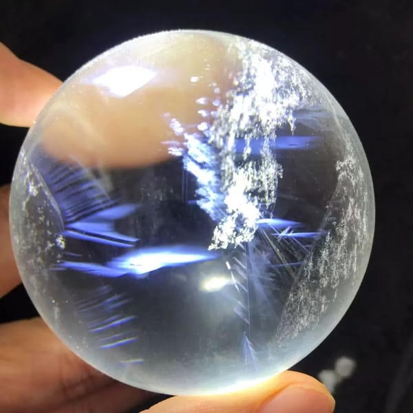 Blue needle quartz sphere with white snowflake clusters and deep blue zones
