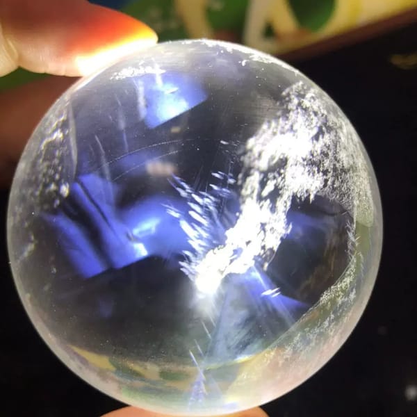 Platy blue needles and white flakes fanning across the clear polished sphere
