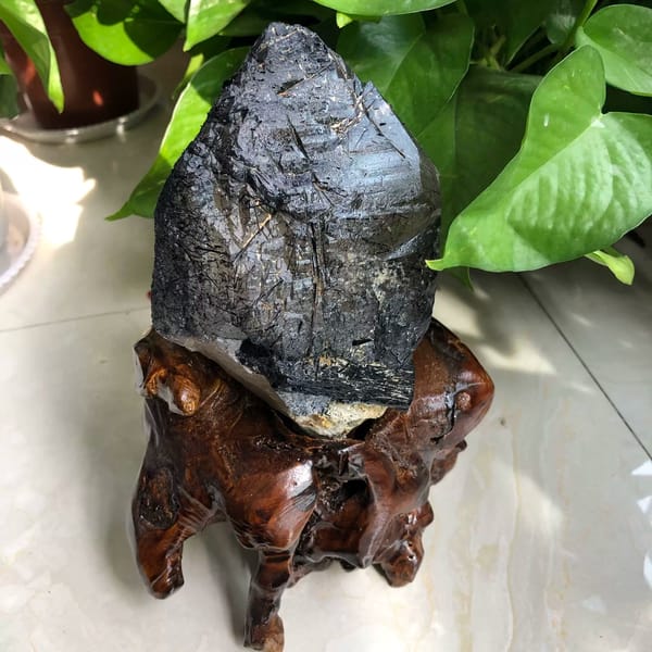 Pointed rough crystal with dark needles visible through grey quartz