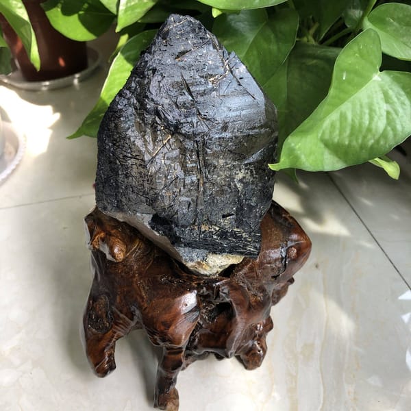 Crystal seated on its root stand showing needle-filled faces and tip