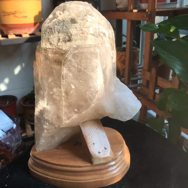 Large rough quartz crystal on a wooden base with a dark phantom under the tip