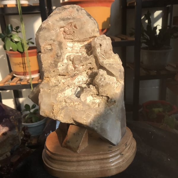 Rough crusty reverse of the crystal seated on the wooden display base