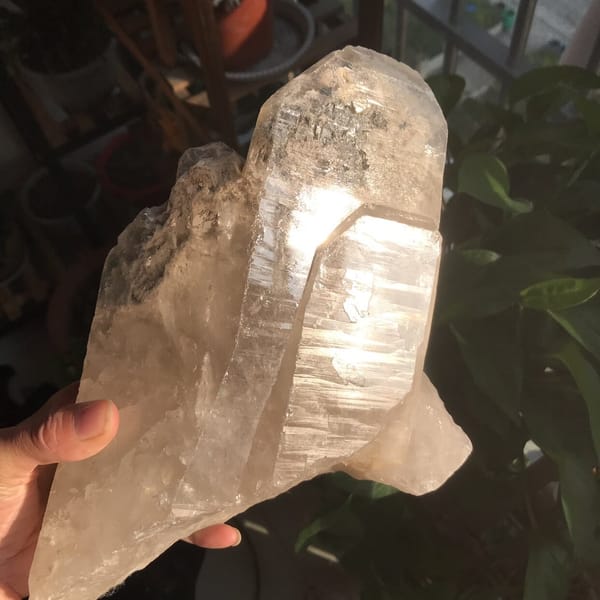 Crystal held in hand showing bright, deeply striated prism faces