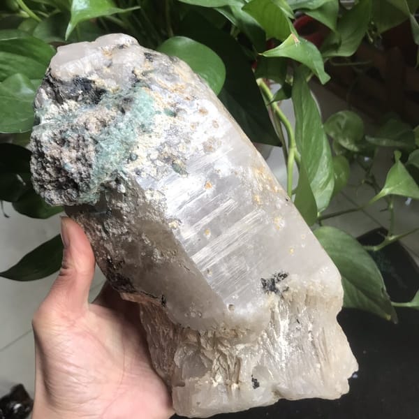 Specimen held in hand with tourmaline cap and striated quartz faces