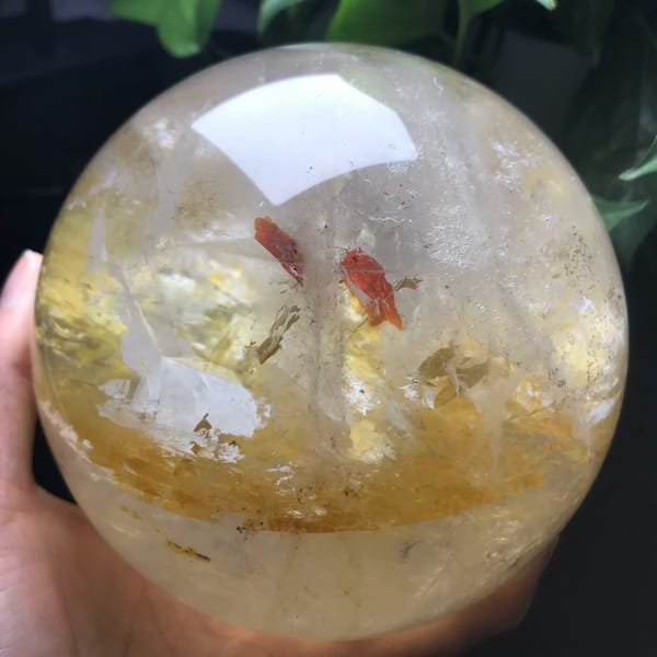 Red fire quartz sphere with a golden inclusion band and two red flakes