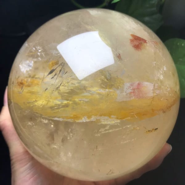 Golden-yellow band sweeping across the clear sphere with a red flake above