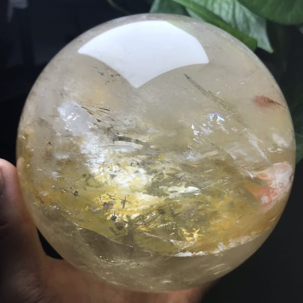 Sphere in hand with yellow inclusions and a red patch on the right
