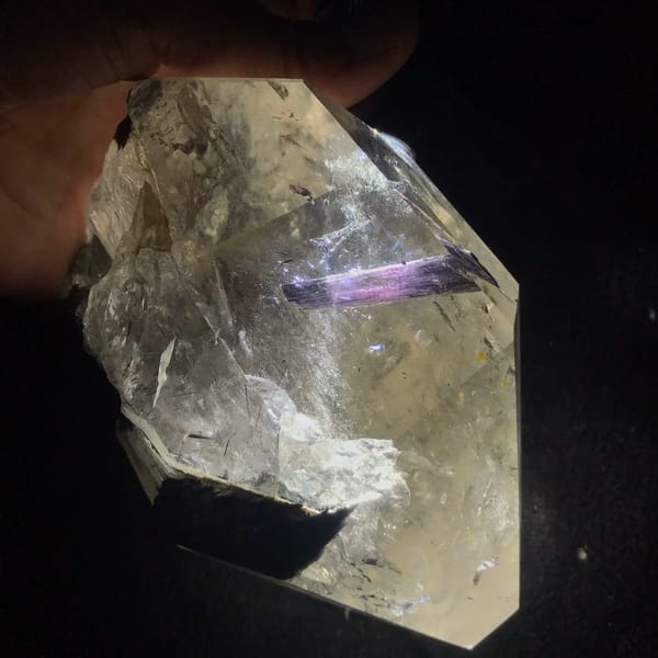 Backlit quartz on a dark background with a purple tourmaline crystal inside