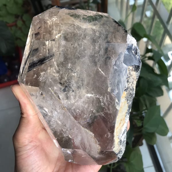 Clear polished face with dark tourmaline at the right and a rough edge