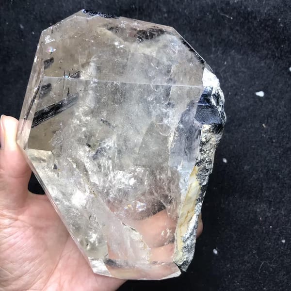 Quartz on black cloth with dark tourmaline and a natural rough edge