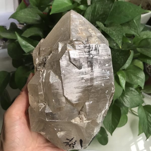 Clear stepped faces and white crust patches on the lower crystal