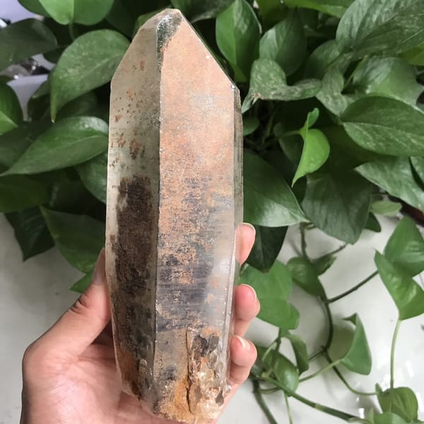 Orange-brown starry speckles across a face of the quartz point
