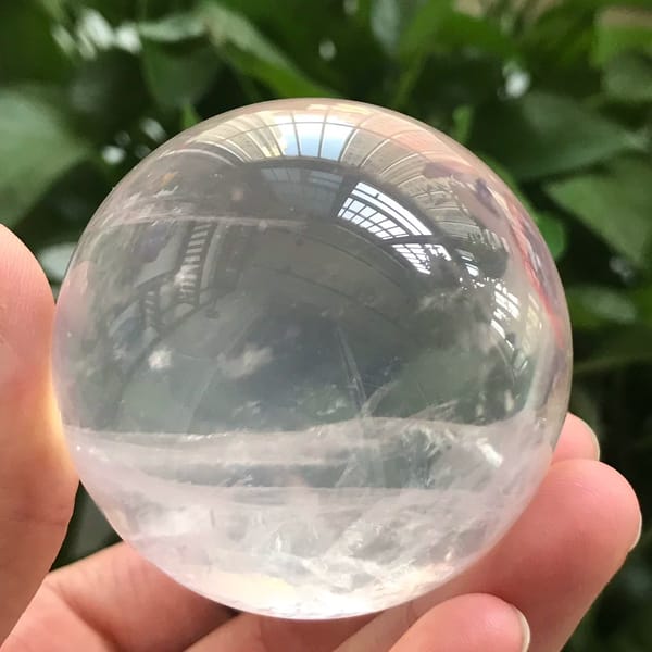 Pale pink sphere against leaves showing its icy transparency