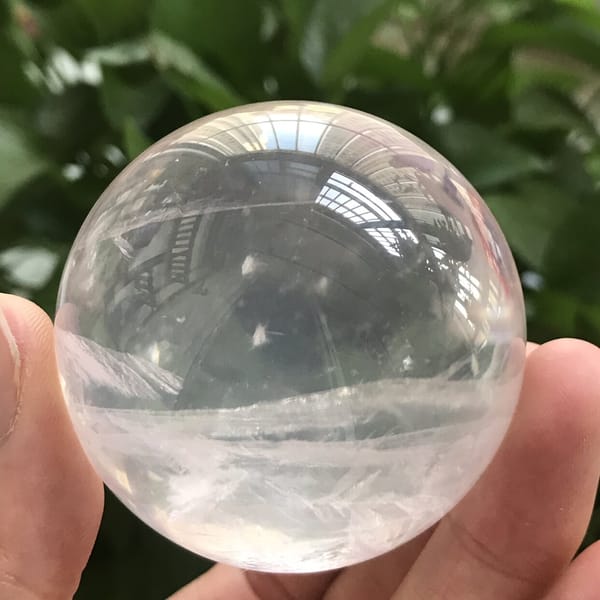 Pink sphere against greenery with wispy white snowflake inclusions
