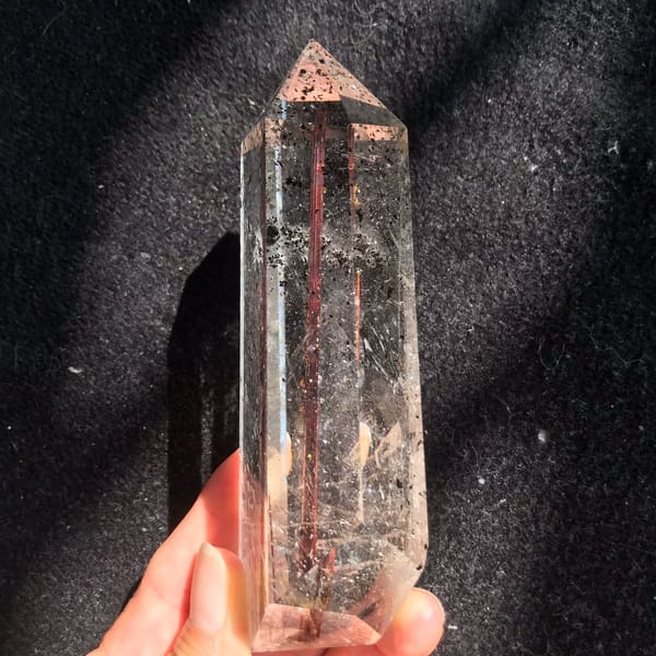 Copper rutile needle centred in the clear point against dark cloth
