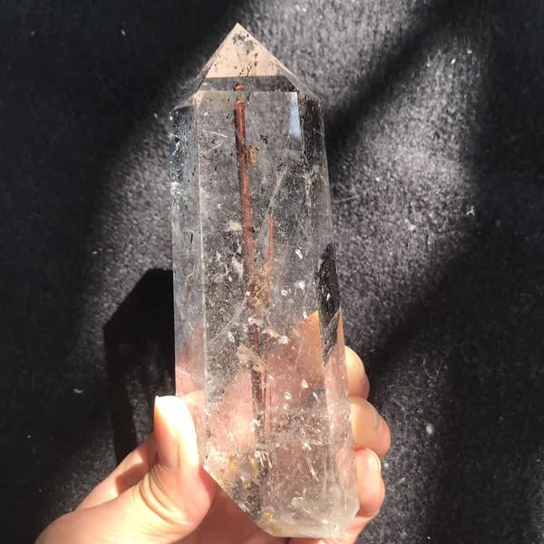 Clear faces with fine needles and scattered dark phantom flecks