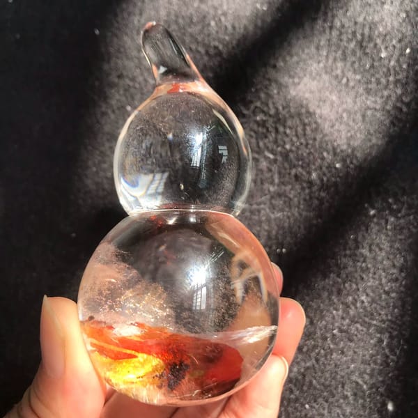 Clear quartz gourd with red and yellow fire inclusions in the lower bulb