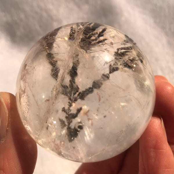 Polished sphere showing the tree trunk and pinkish wisps around it