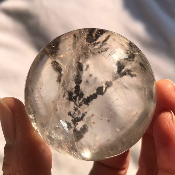 Dark branches spreading upward through the clear quartz ball