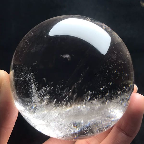 Clear quartz sphere with a band of white mist across its lower half