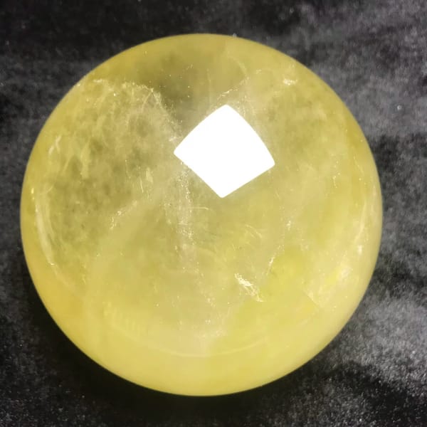 Citrine sphere with white veils drifting across the yellow body