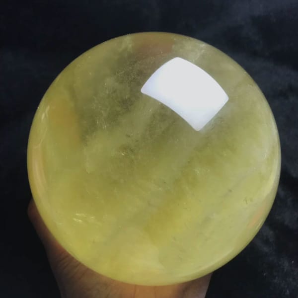 Citrine sphere held in hand showing layered yellow colour