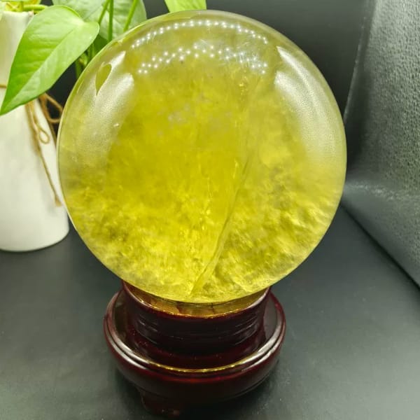 Bright yellow citrine sphere with streaky inclusions on its stand