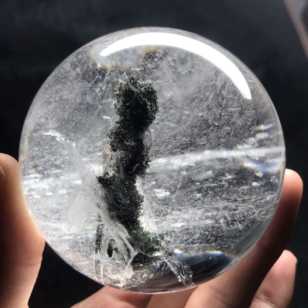 Clear quartz sphere with a tall dark green mossy phantom column