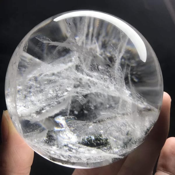 Lace-like white veils and a green fleck at the base of the sphere