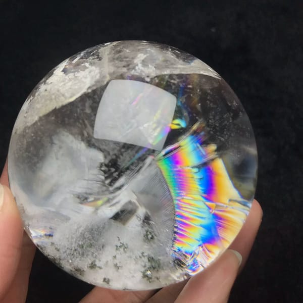 Garden quartz sphere with a bold rainbow arc and green speckles